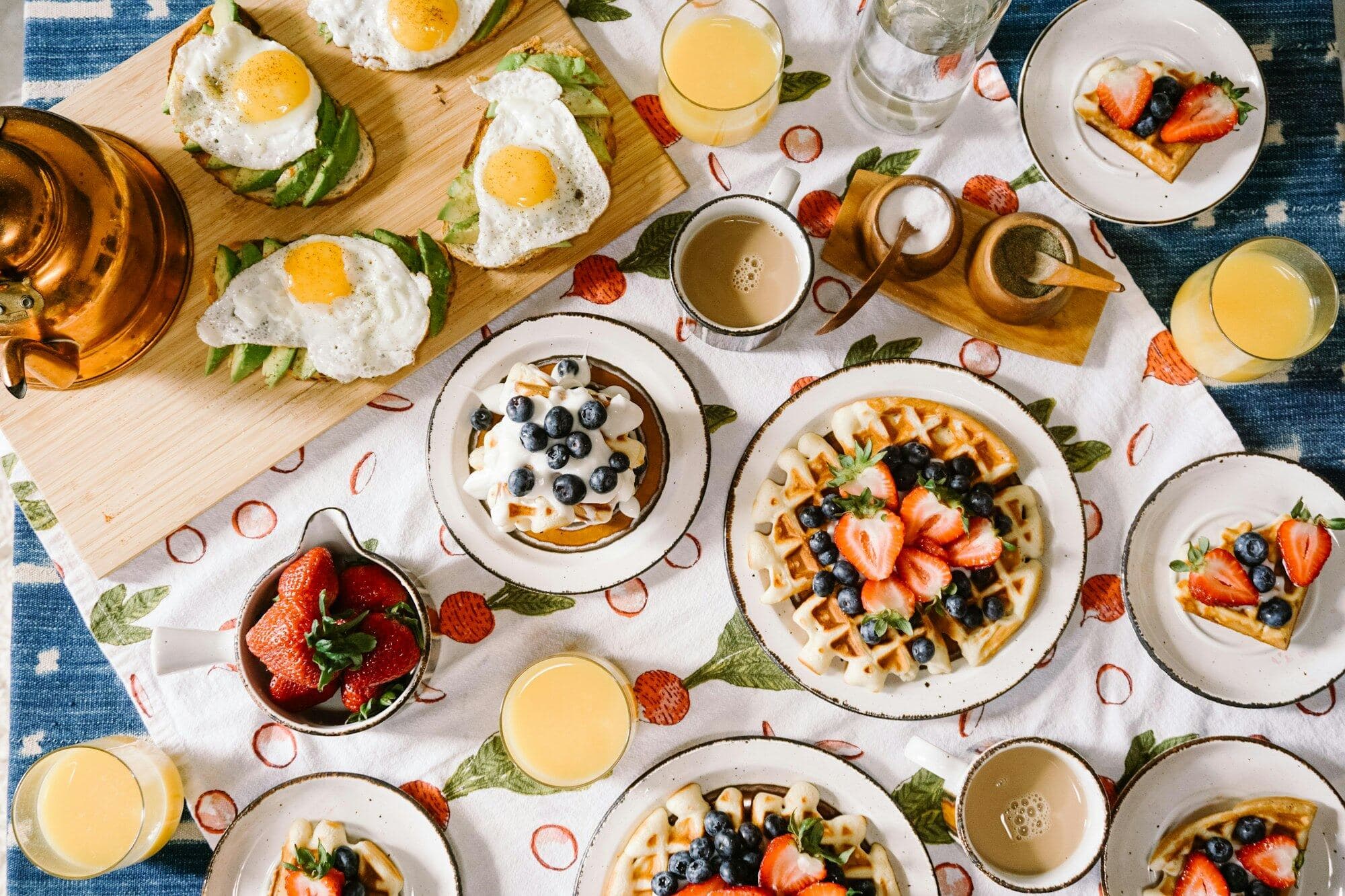 Mesa de brunch com waffles, ovos e frutas